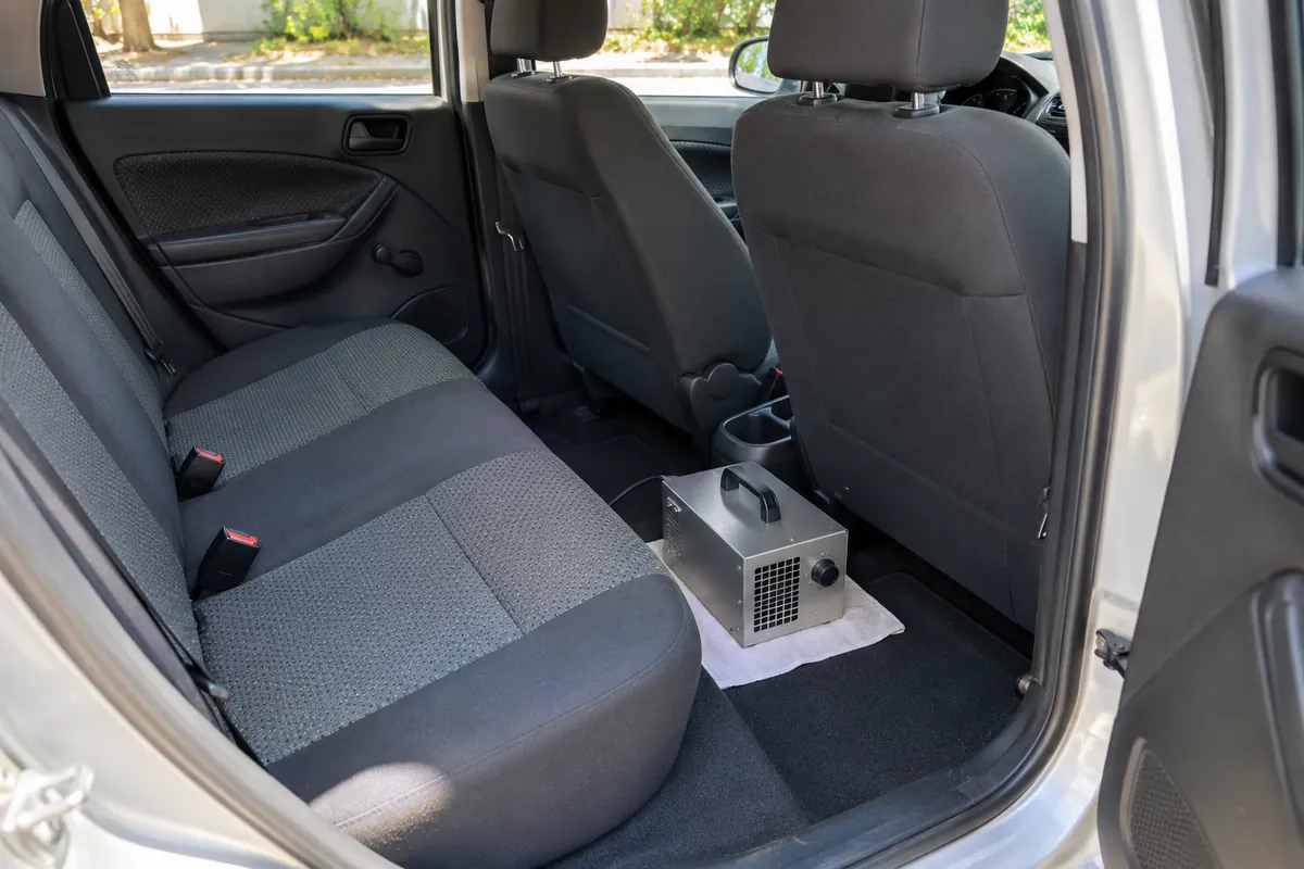 Gerador de ozônio no assoalho de um carro vazio, com a porta aberta.